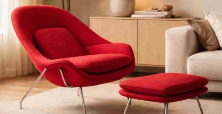 Poltrona di design rossa con pouf coordinato in un soggiorno moderno, palette neutra calda e dettagli in stile Bauhaus.